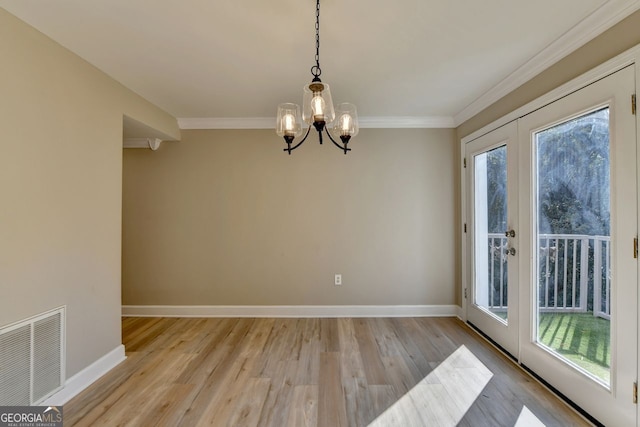 unfurnished dining area featuring ornamental molding, light hardwood / wood-style floors, and a notable chandelier