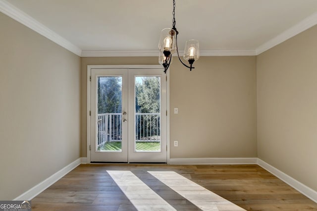 unfurnished dining area with light hardwood / wood-style floors, french doors, ornamental molding, and a chandelier