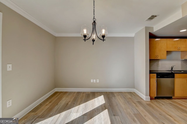 unfurnished dining area with sink, light hardwood / wood-style flooring, ornamental molding, and an inviting chandelier