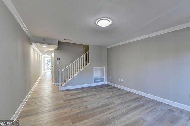 empty room featuring ornamental molding, light hardwood / wood-style floors, and built in shelves