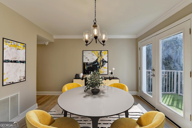 dining room featuring ornamental molding, a chandelier, and light wood-type flooring