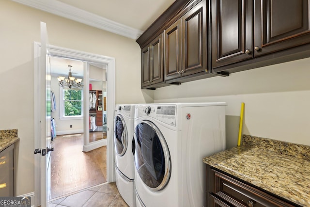 laundry room featuring cabinets, crown molding, light tile patterned floors, separate washer and dryer, and an inviting chandelier