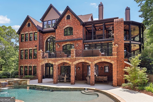 rear view of house featuring outdoor lounge area, ceiling fan, a swimming pool with hot tub, a balcony, and a patio