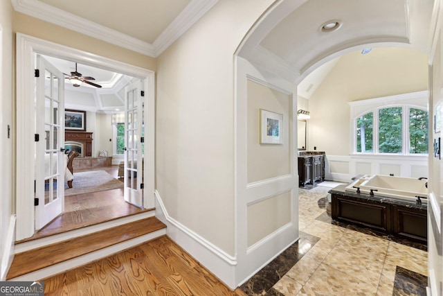 corridor with vaulted ceiling, ornamental molding, french doors, and light hardwood / wood-style flooring