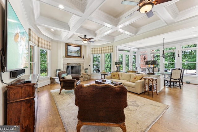 living room with a wealth of natural light, ceiling fan, and coffered ceiling