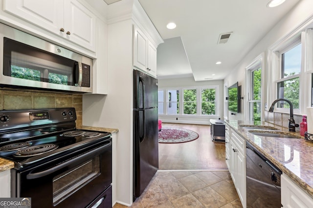 kitchen with black appliances, sink, light tile patterned floors, light stone counters, and white cabinetry