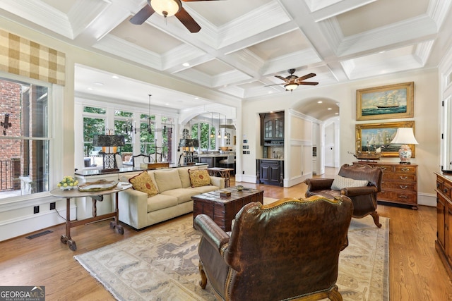 living room featuring ceiling fan, light hardwood / wood-style flooring, beamed ceiling, and coffered ceiling