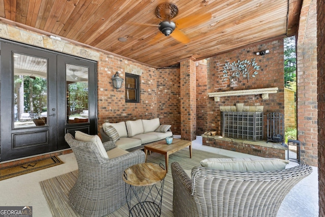 living room with ceiling fan, a wealth of natural light, wooden ceiling, and brick wall