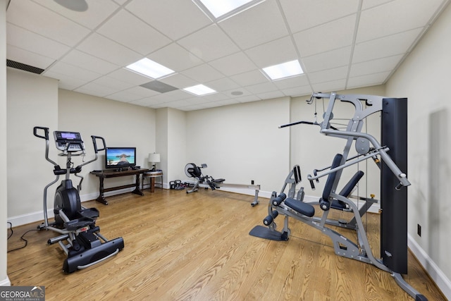 exercise room with a paneled ceiling and hardwood / wood-style flooring