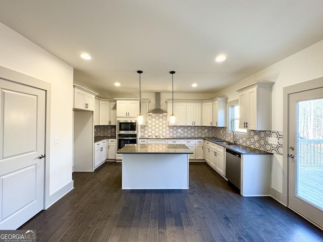 kitchen featuring stainless steel appliances, white cabinetry, wall chimney exhaust hood, and pendant lighting