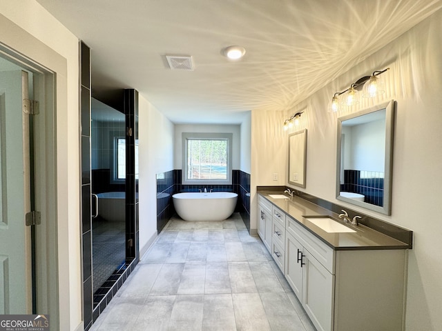 bathroom with vanity, separate shower and tub, and tile walls