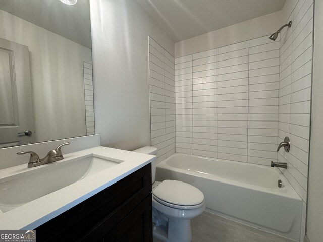 full bathroom featuring tiled shower / bath combo, toilet, and vanity