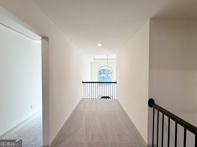 corridor with carpet flooring and a notable chandelier