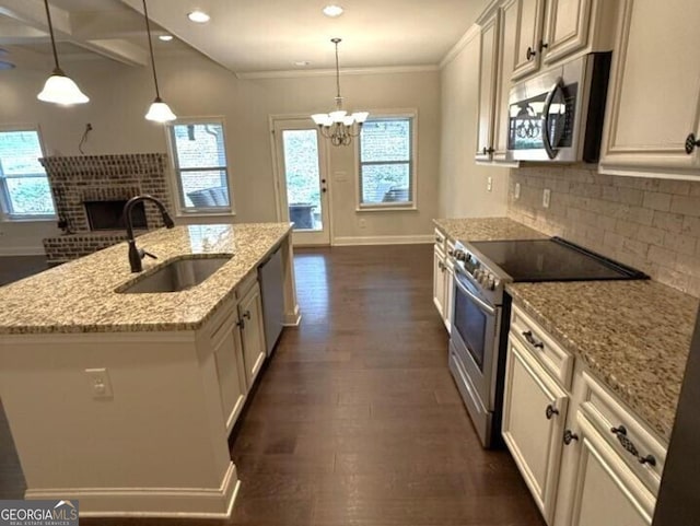 kitchen featuring stainless steel appliances, sink, a center island with sink, and hanging light fixtures