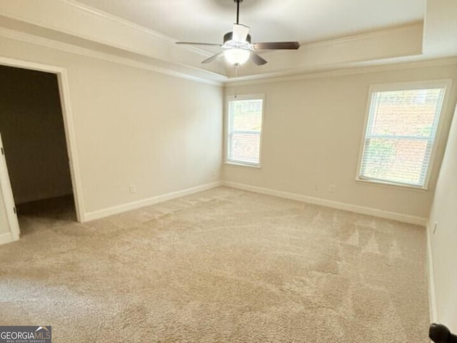 carpeted empty room featuring ornamental molding, a tray ceiling, and ceiling fan