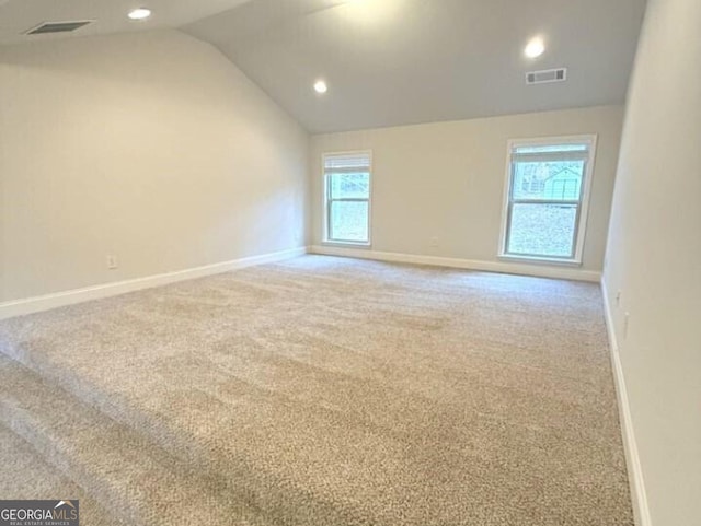 carpeted spare room with a healthy amount of sunlight and vaulted ceiling