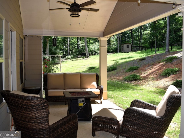 view of patio with ceiling fan, an outdoor living space with a fire pit, and a shed