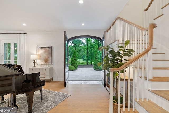 entrance foyer featuring light wood-type flooring, a healthy amount of sunlight, and crown molding