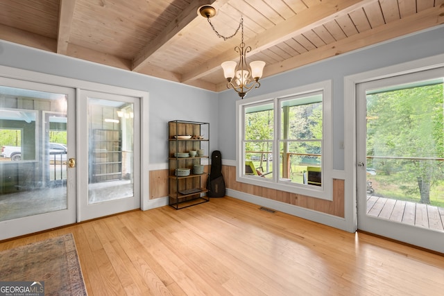 unfurnished sunroom featuring beamed ceiling, a notable chandelier, a wealth of natural light, and wooden ceiling