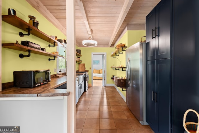 kitchen with butcher block counters, wood ceiling, beamed ceiling, appliances with stainless steel finishes, and light tile floors