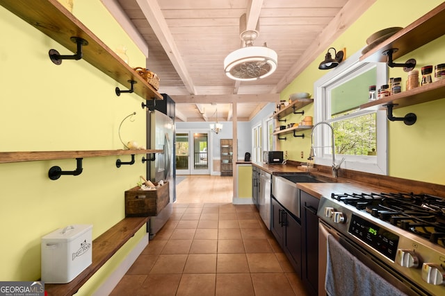 kitchen with tile flooring, beam ceiling, wood ceiling, appliances with stainless steel finishes, and pendant lighting