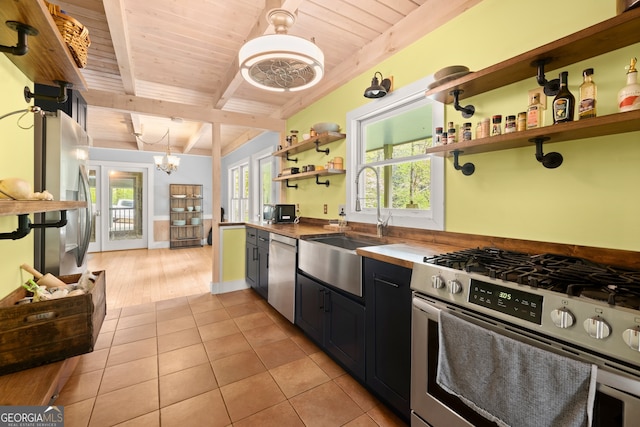 kitchen with hanging light fixtures, stainless steel appliances, wooden ceiling, sink, and light tile flooring