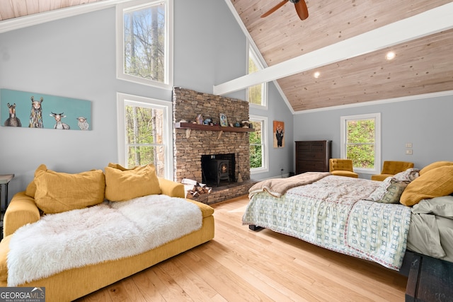 bedroom featuring a stone fireplace, multiple windows, light wood-type flooring, and wooden ceiling