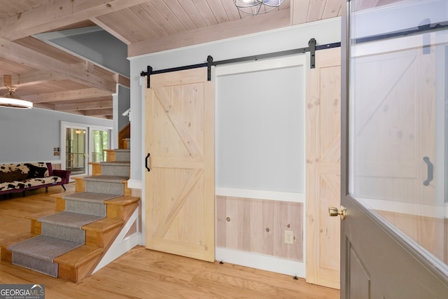 stairway with a barn door, beam ceiling, and wood ceiling