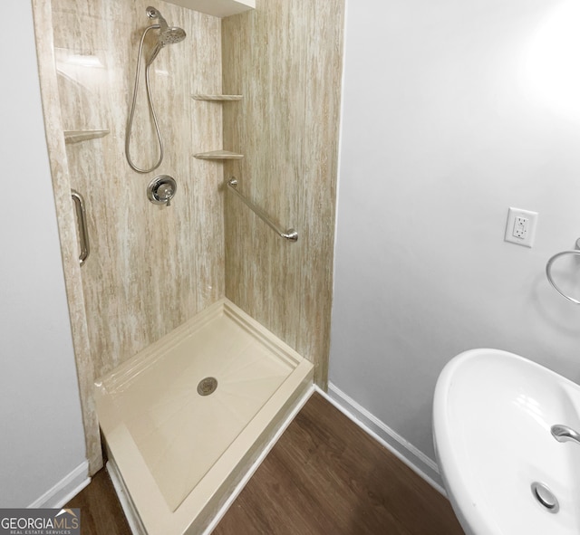 bathroom featuring a tile shower, sink, and wood-type flooring