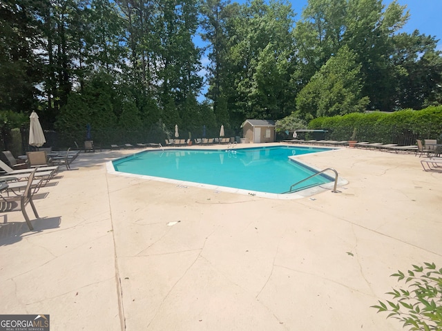 view of pool with a patio area and a shed