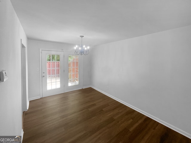 empty room with an inviting chandelier and dark wood-type flooring