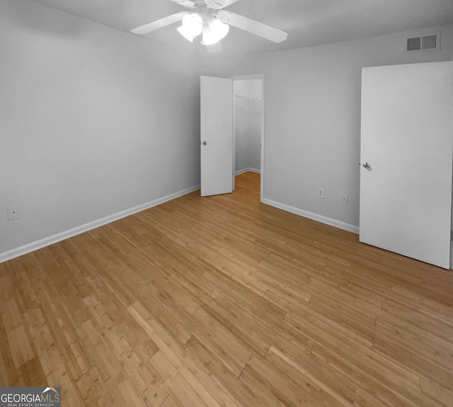 unfurnished bedroom with ceiling fan, light hardwood / wood-style floors, and a spacious closet