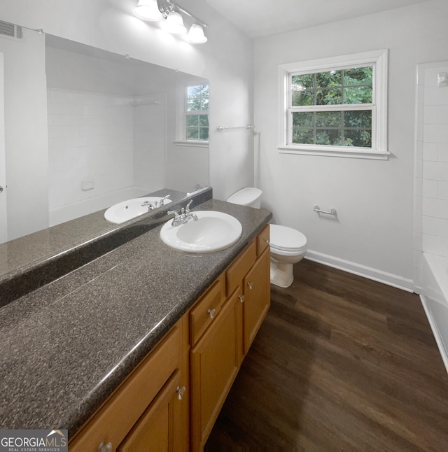 full bathroom featuring a healthy amount of sunlight, hardwood / wood-style floors, toilet, and vanity