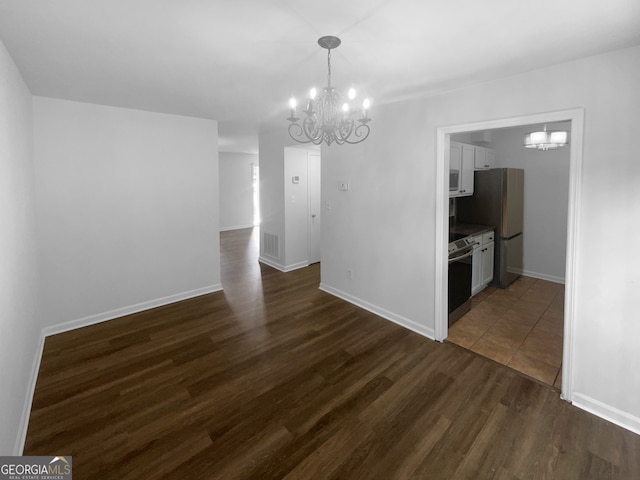 tiled spare room featuring a notable chandelier