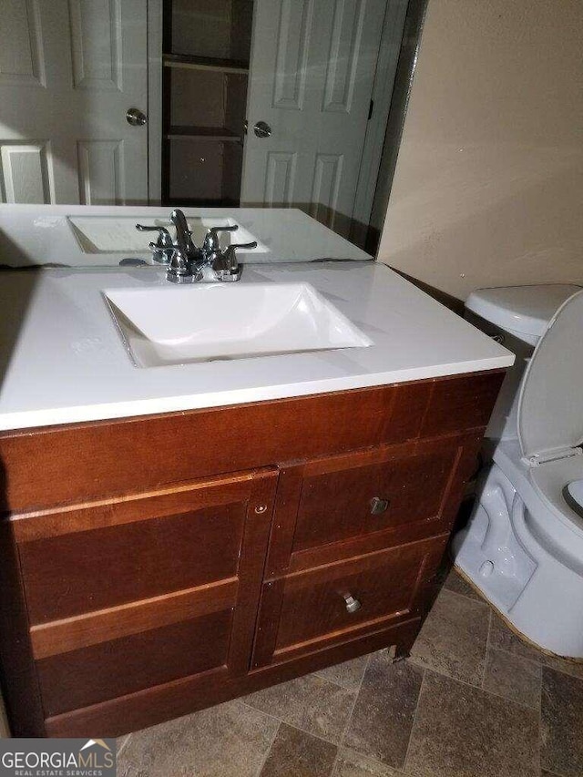 bathroom featuring tile flooring, vanity, and toilet