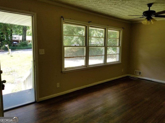 empty room with dark hardwood / wood-style floors, plenty of natural light, ceiling fan, and crown molding