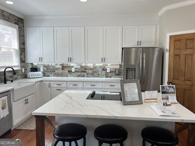 kitchen featuring white cabinets, appliances with stainless steel finishes, a breakfast bar, and sink