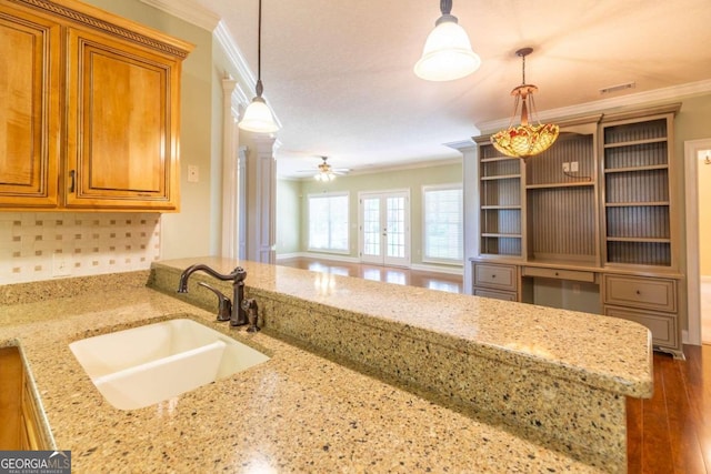 kitchen featuring sink, ornamental molding, light stone counters, and hardwood / wood-style floors