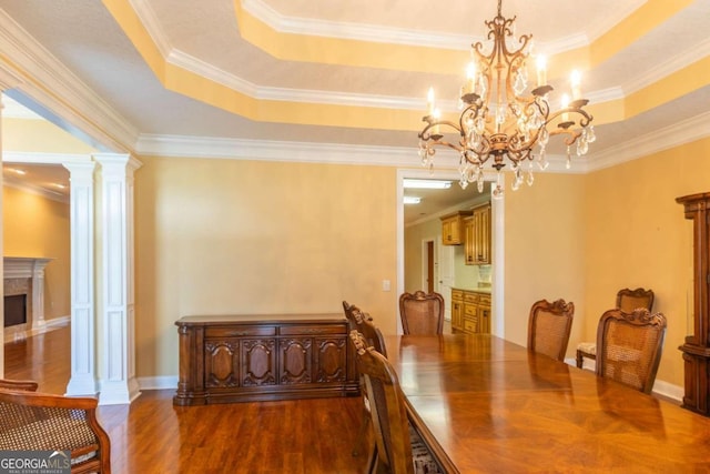 dining space with a premium fireplace, wood-type flooring, a raised ceiling, and crown molding