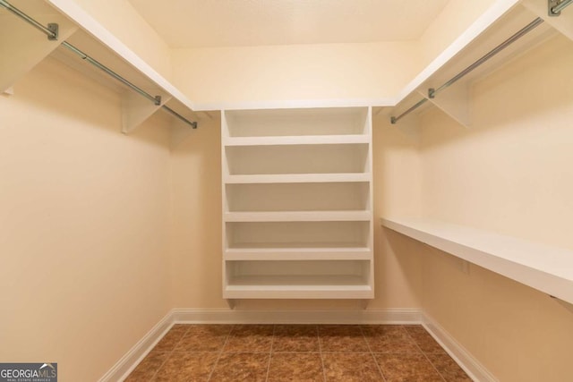 spacious closet with dark tile flooring