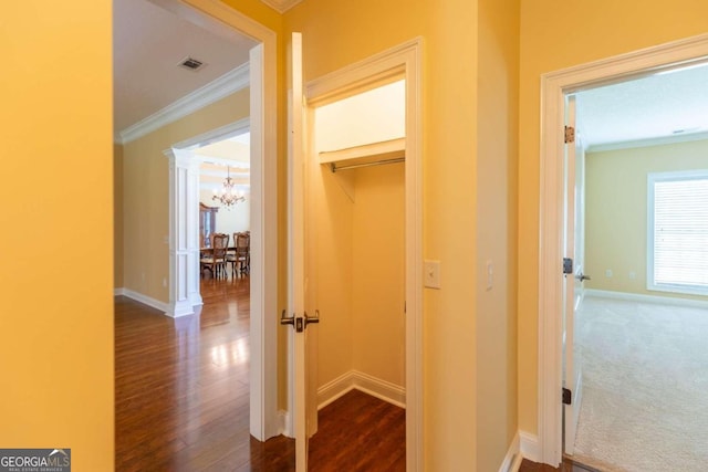 corridor with ornamental molding, dark carpet, and a chandelier