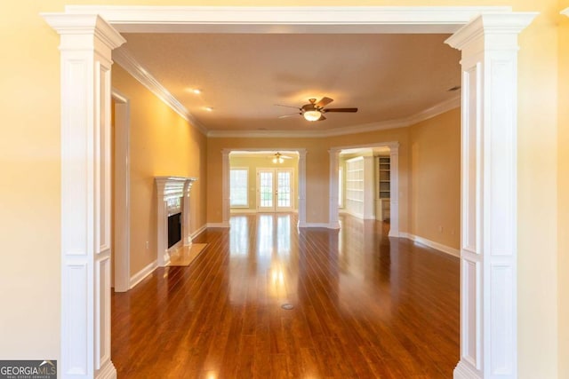 unfurnished living room featuring dark hardwood / wood-style floors, a premium fireplace, ceiling fan, and crown molding