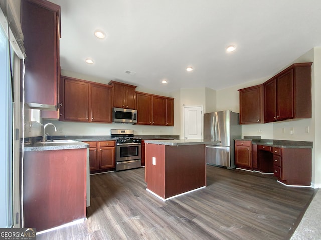 kitchen featuring appliances with stainless steel finishes, sink, a center island, and dark hardwood / wood-style flooring