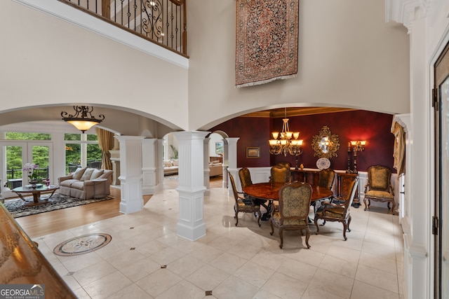 dining area with tile flooring, french doors, decorative columns, a notable chandelier, and a high ceiling