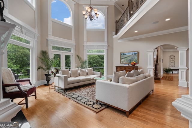 living room featuring a wealth of natural light, a towering ceiling, and light hardwood / wood-style flooring