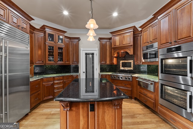 kitchen with a kitchen island, stainless steel appliances, hanging light fixtures, tasteful backsplash, and light wood-type flooring