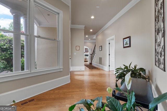 entrance foyer with ornamental molding, light hardwood / wood-style floors, and a wealth of natural light