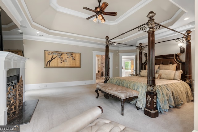 bedroom with crown molding, carpet floors, a premium fireplace, and a raised ceiling