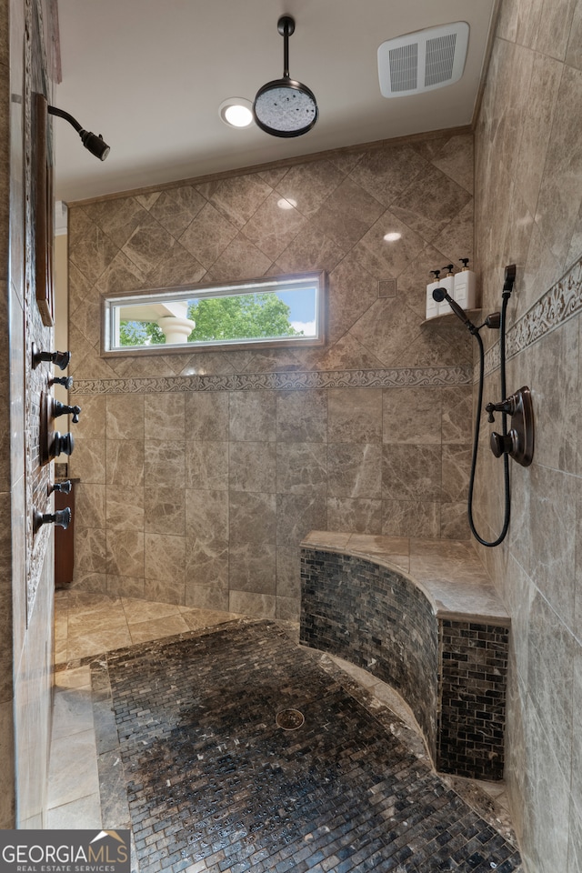 bathroom featuring a tile shower, tile flooring, and plenty of natural light