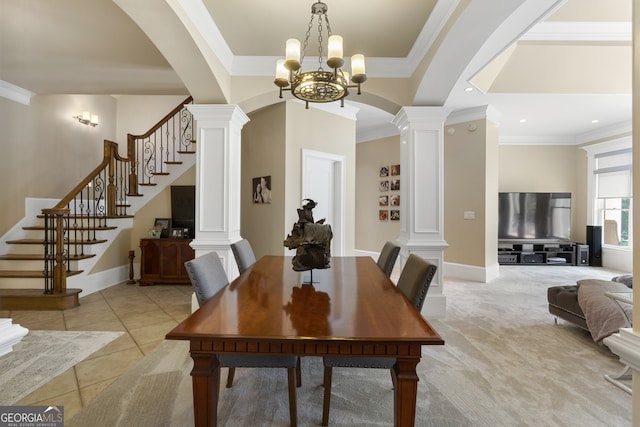 carpeted dining area featuring ornamental molding, a chandelier, and decorative columns